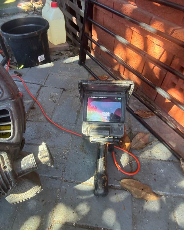 A drain camera screen beside an open inspection point