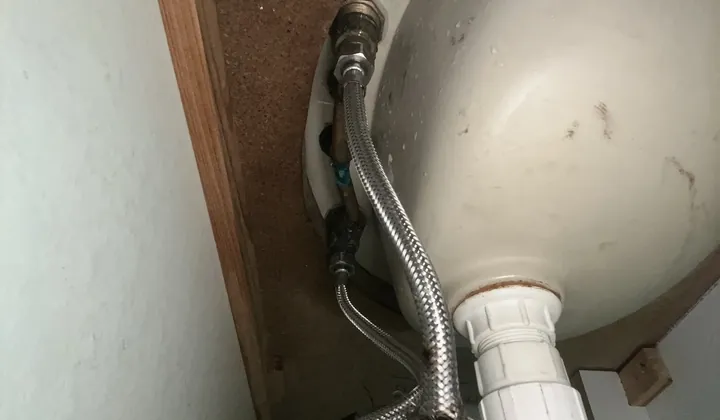 Frayed and burst braided flexi hose under a bathroom basin