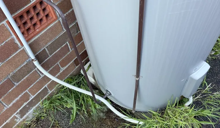 Blue-capped valve on the copper water line next to a storage tank and brick vent in Riverwood
