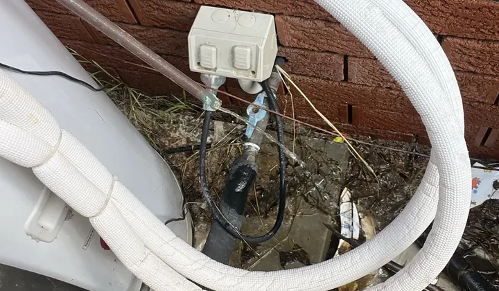 White lagged hot water pipes and a power point beside an outdoor tank in Seven Hills