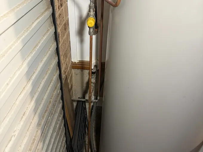 Valves and a braided hose on the water connections of an electric hot water system in Illawong
