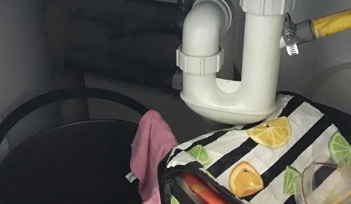 White plastic trap and waste pipe under a blocked kitchen sink in Centennial Park