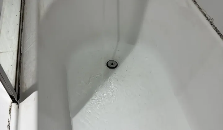 Bath spout running, with water collecting around the plughole in Newtown