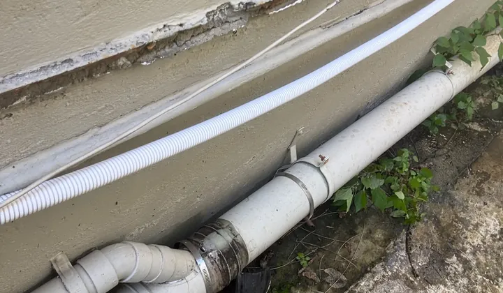 Plastic waste pipes and a rubber joint along the outside wall of a house in Newtown