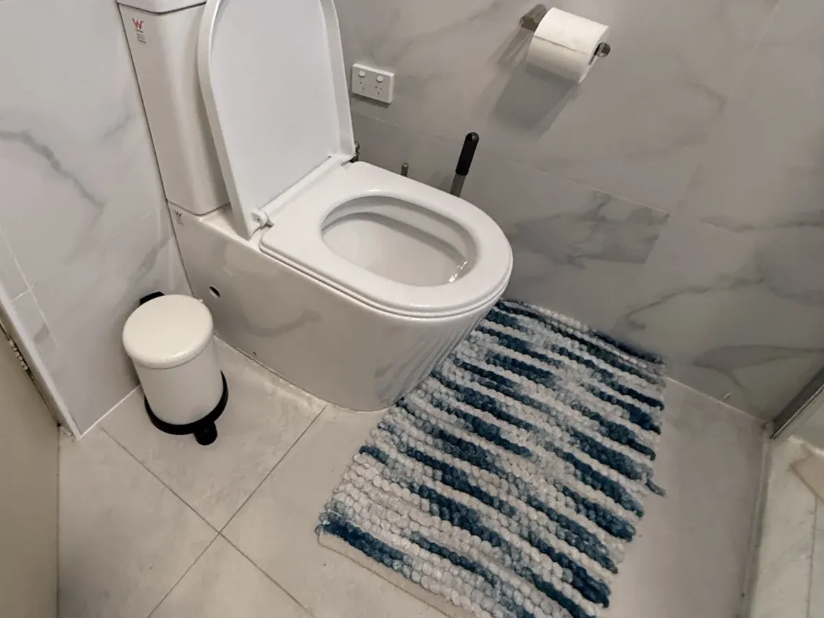 Marble-tiled bathroom with the toilet lid up in Gordon