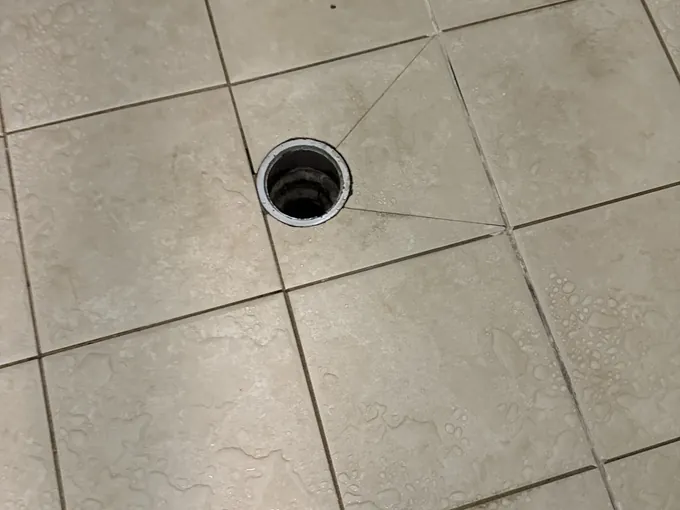 Wet shower floor tiles with the round waste grate removed in Granville