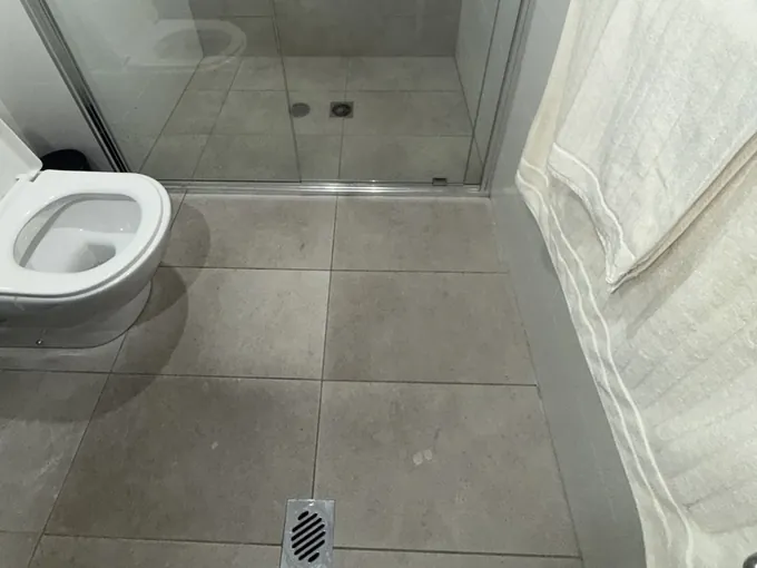 Walk-in shower and its floor waste beside the toilet in a tiled bathroom in Belmore