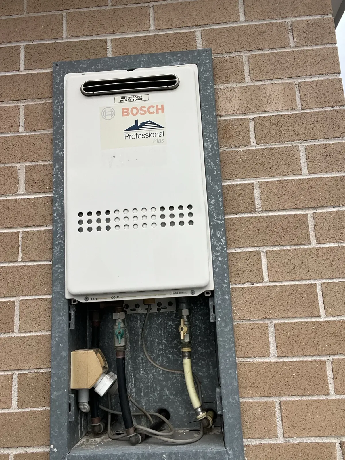 Bosch Hot Water Sydney - Bottom of a gas continuous flow unit and its hot, cold and gas valves in a recess box in Canterbury