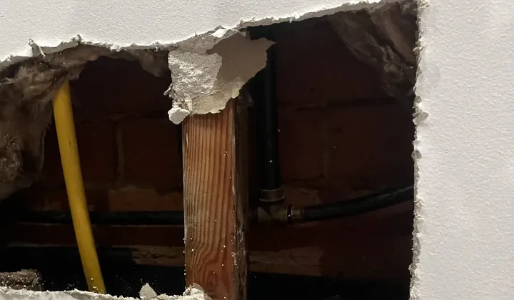 Hole cut in a plasterboard wall to reach the pipes behind it in Oran Park