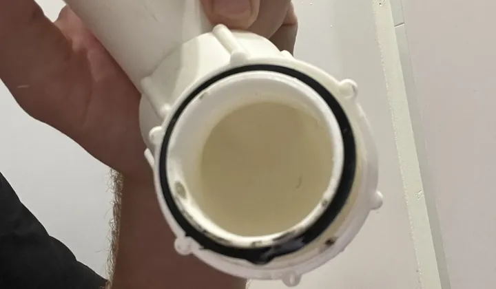 Plumber holding a length of white plastic waste pipe and its joint in North Rocks