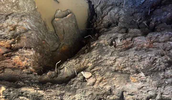 Old terracotta sewer pipe at the bottom of a deep, water-filled hole in Newtown