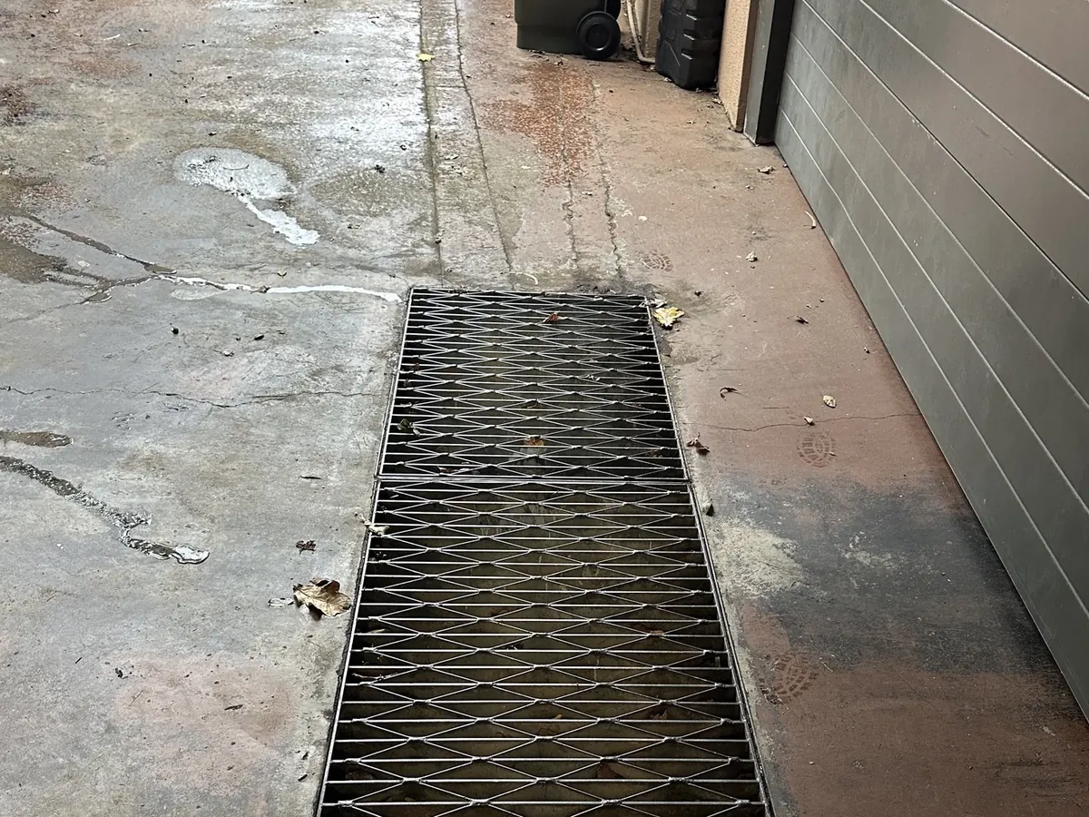 Water trails running across a concrete driveway to a drain grate in Naremburn