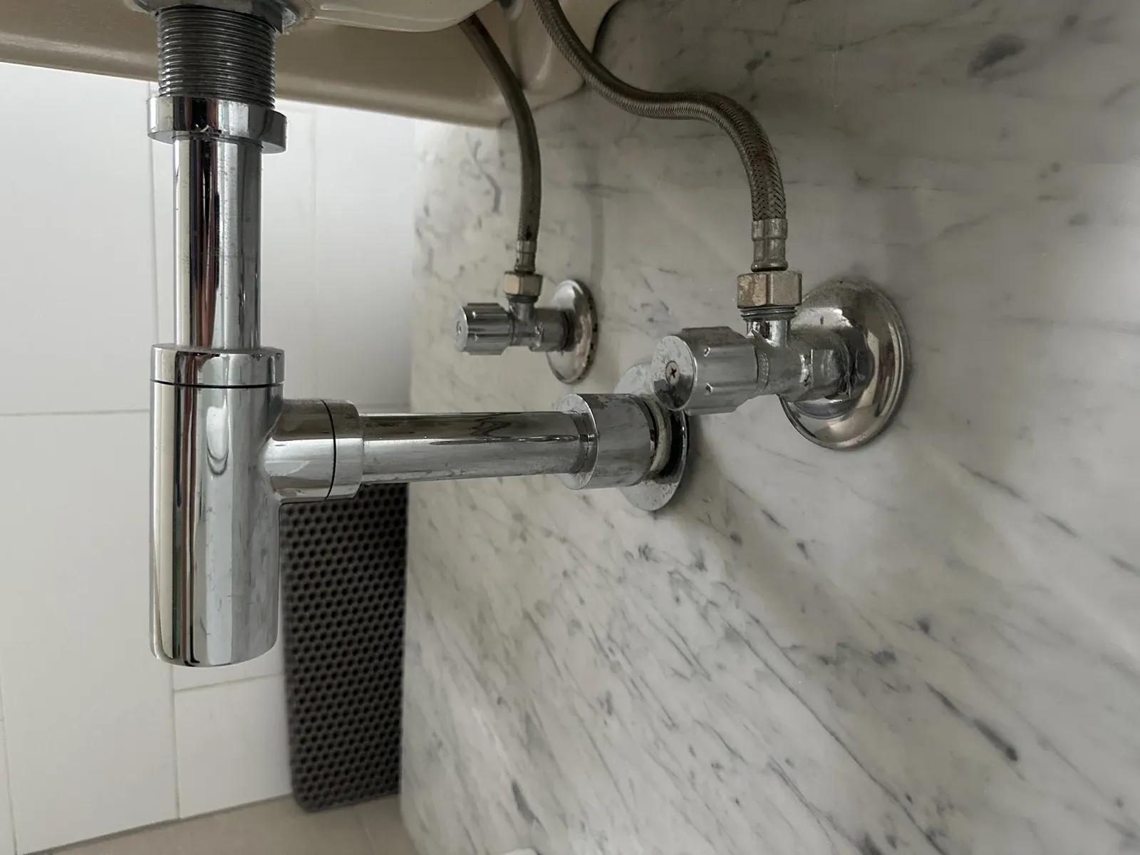 Braided flexi hoses and chrome isolation taps under a basin on a marble wall in Alexandria