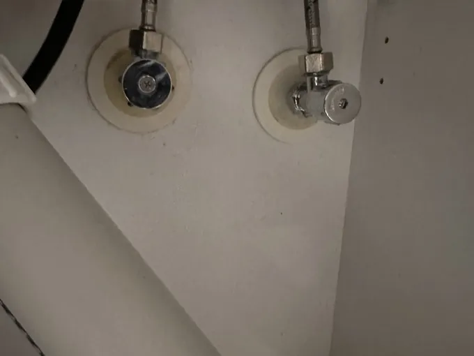 Two isolation taps with braided hoses under a sink in Roselands