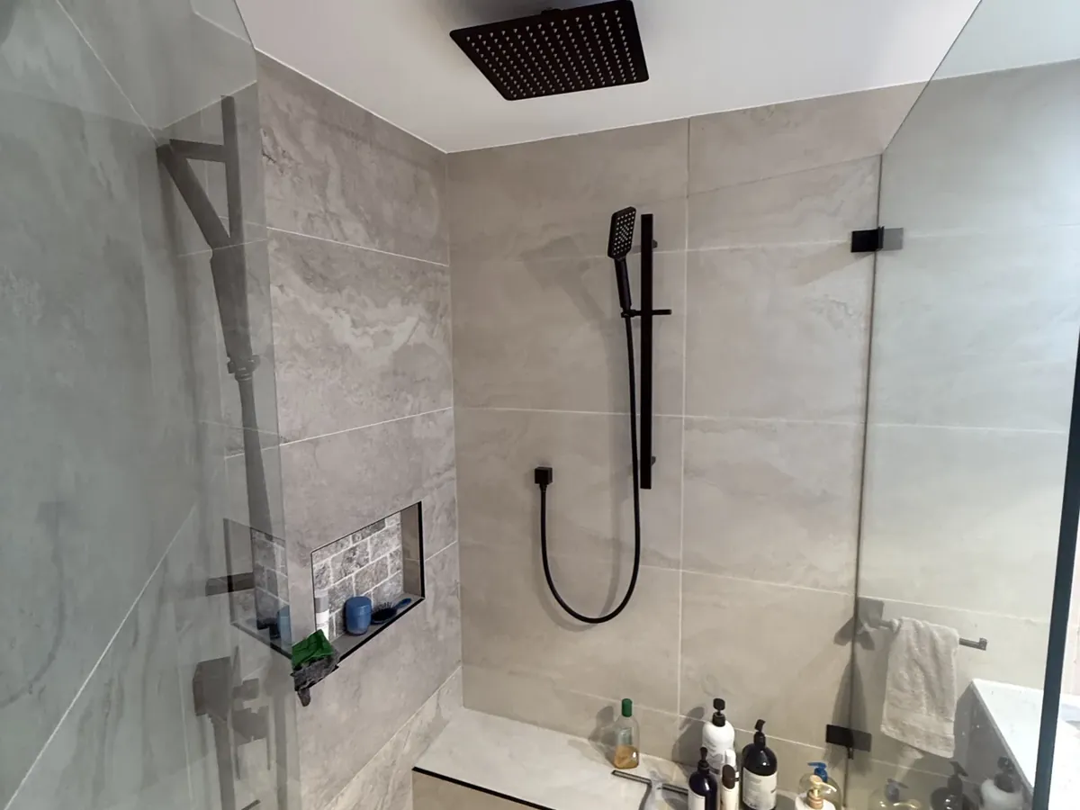 Walk-in shower with a rain head and hand shower on the level above the leak in Beverly Hills