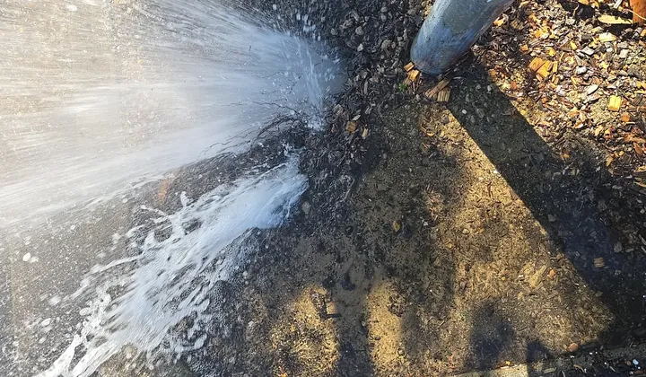 Water jetting out of the ground beside a fire hydrant riser at a business in Villawood