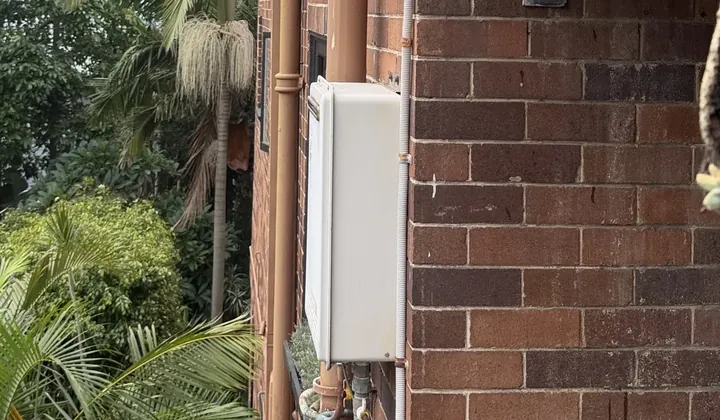 Continuous flow hot water unit and its pipes on the brick wall of an apartment block in Bondi Beach