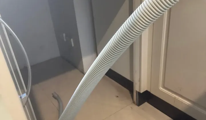 Empty dishwasher space with a long drain hose laid across the kitchen tiles in Glen Alpine