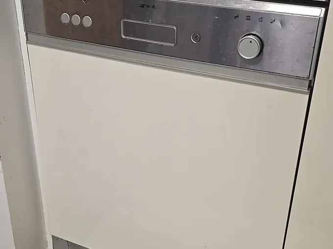 Built-in dishwasher with a stainless control panel under a white kitchen bench in Ultimo