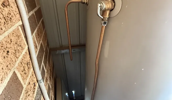 Relief valve and copper drain pipe on the side of an electric hot water tank