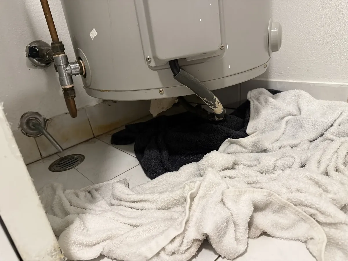 Towels on a laundry floor soaking up water leaking from under a hot water tank