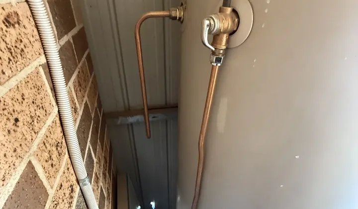 Relief valve and copper drain line on the side of an electric hot water tank in a narrow passage in Austral