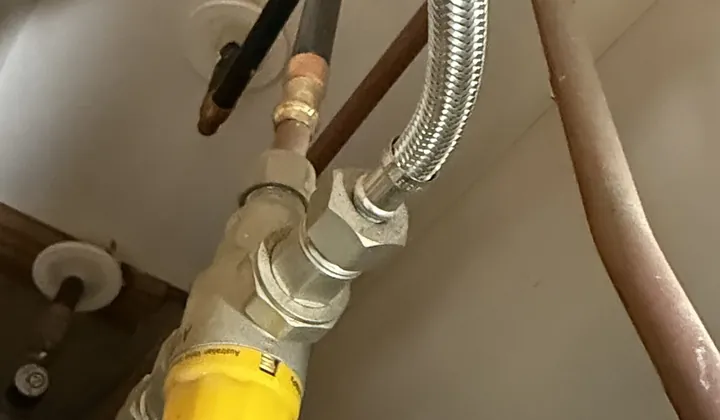 Braided hose joined to a yellow-capped valve on copper water pipes in Illawong
