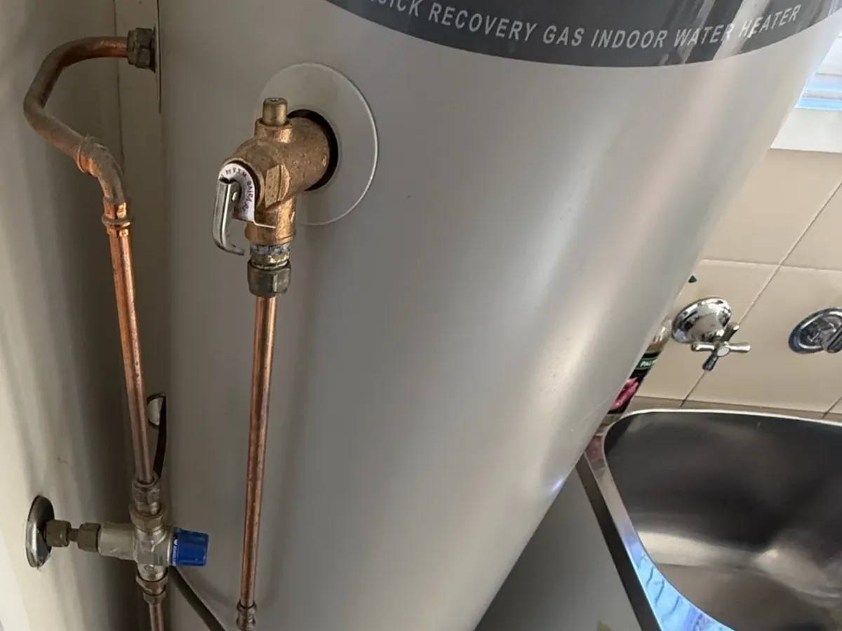 Relief valve with its lever and copper drain pipe on an indoor gas storage hot water tank in Tempe