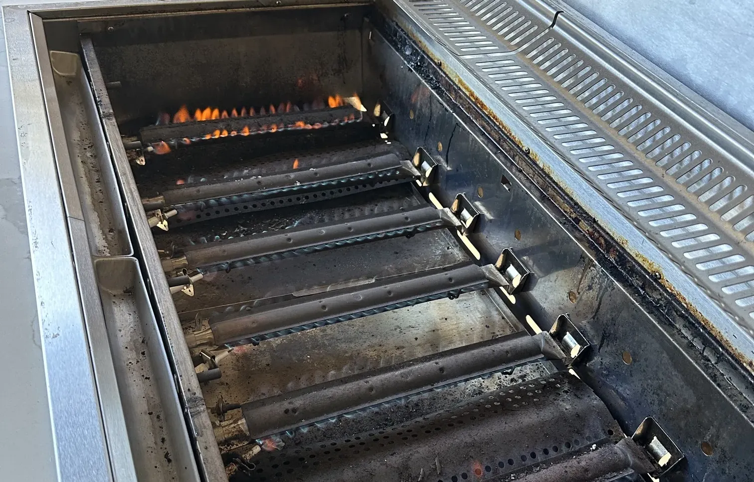 Burners lit inside a built-in stainless steel gas BBQ in an outdoor kitchen in Condell Park