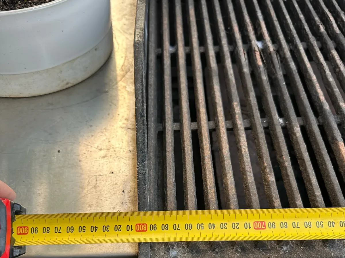 Tape measure held across the grill plates of an outdoor gas BBQ being measured up in Quakers Hill