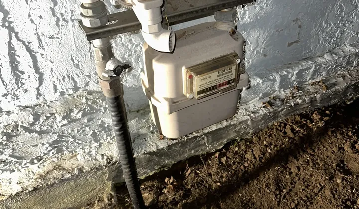 Gas meter on a rendered wall with a trench dug beside it for the gas pipe in Earlwood