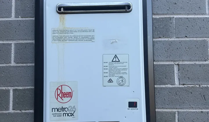 Rheem continuous flow gas hot water unit in a wall recess box on grey brick in Denham Court