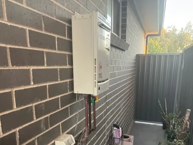 Existing continuous flow gas hot water unit and its copper pipes in a side passage in Oran Park
