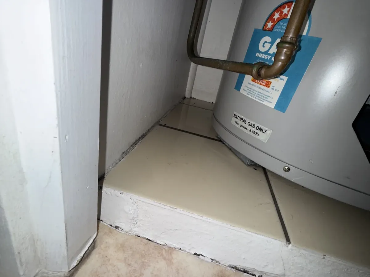 Base of a natural gas storage tank and its copper pipes on a tiled step inside a cupboard in Tempe