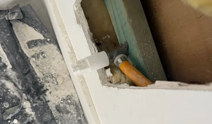 Plasterboard cut open to reach a capped fitting on an orange gas pipe inside the wall cavity in Carramar