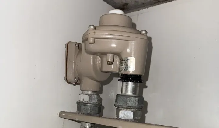 Gas regulator and yellow-handled isolation valve on the gas pipework in a meter cupboard in Parramatta