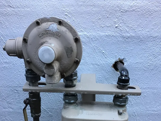 Gas meter, regulator and isolation valve on a rendered wall with leak test fluid on the outlet, in Kellyville