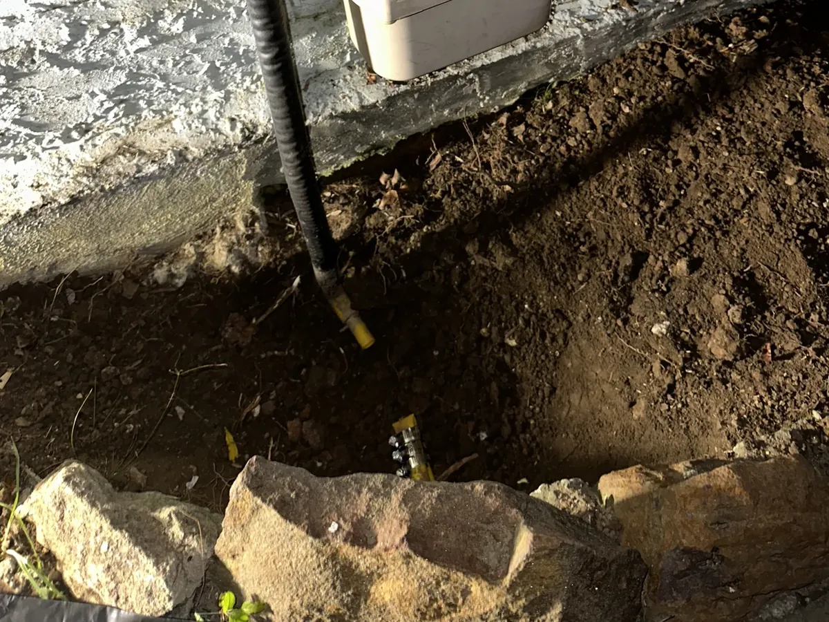 Ground dug out below a gas meter on a rendered wall to reach the gas pipe, in Earlwood
