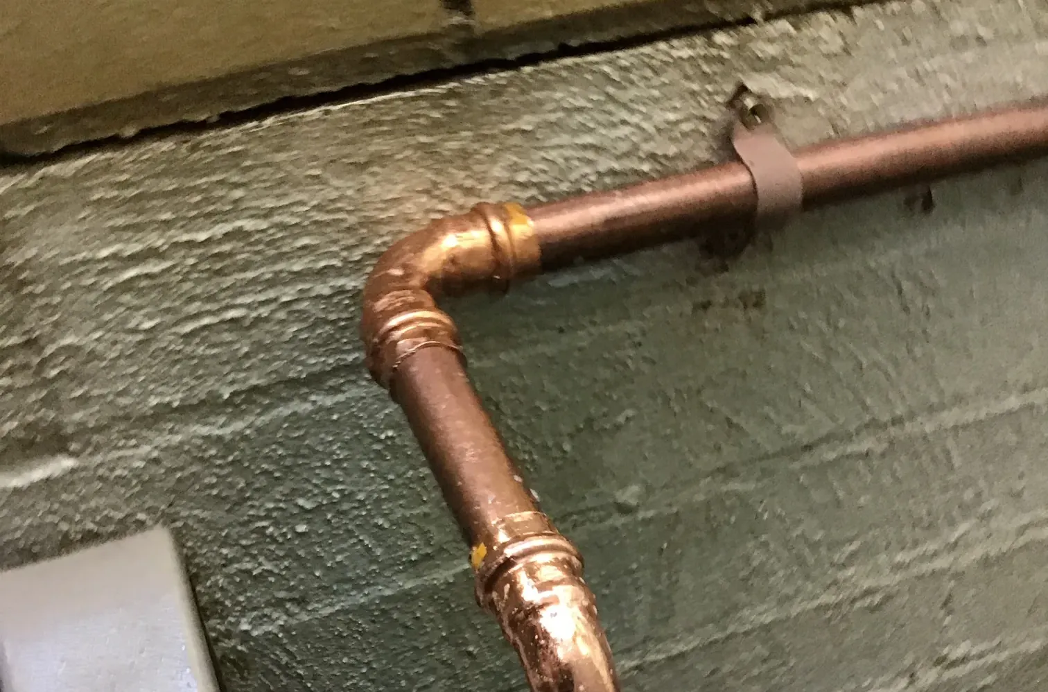New copper gas pipe with press-fit elbows fixed to a painted block wall in Lidcombe