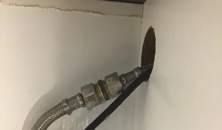 Braided gas hose joined to the gas pipe coming through a cooktop cupboard wall in Pendle Hill