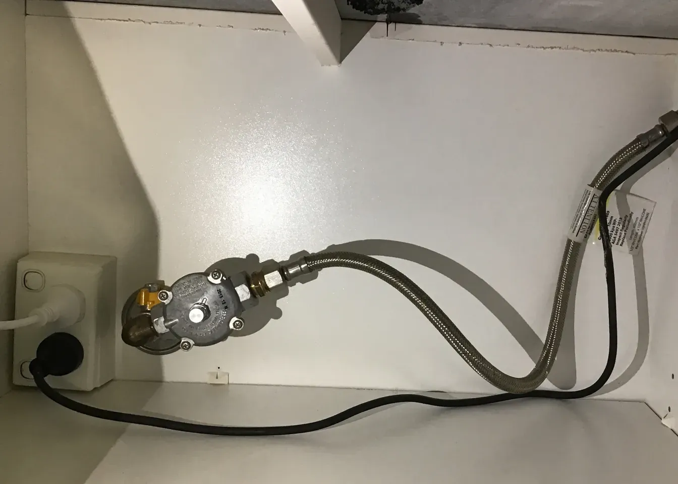 Gas regulator and braided hose connected under a cooktop beside a power point in Pendle Hill