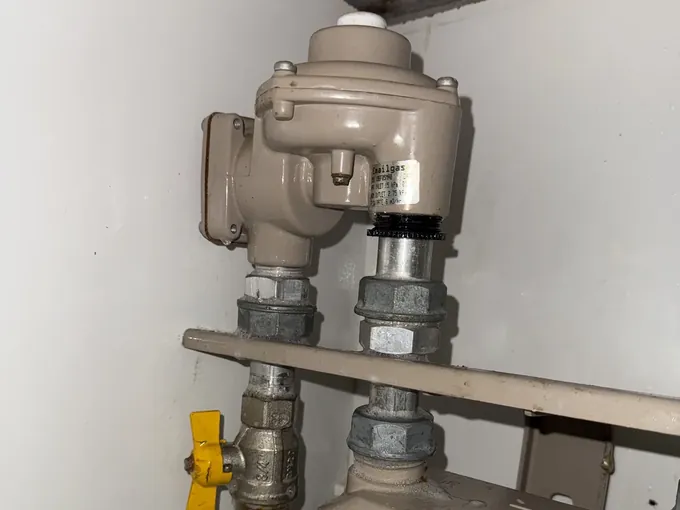 Gas regulator and yellow isolation valve on the gas point inside a cupboard in Parramatta