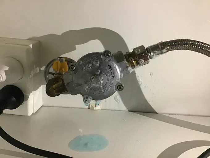 Leak detection fluid sprayed over a gas regulator and hose fitting under a cooktop in Pendle Hill
