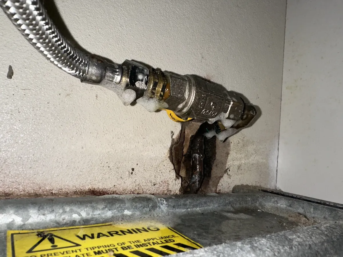 Leak detection fluid on the braided gas hose connection behind a freestanding stove in Collaroy