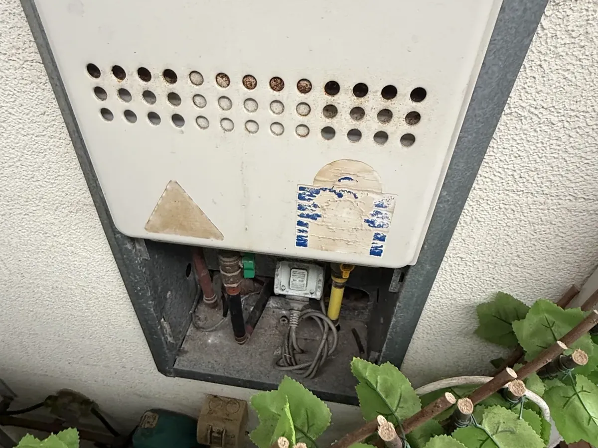 Gas appliance with its lower panel open showing the gas connection and isolation valve in Little Bay