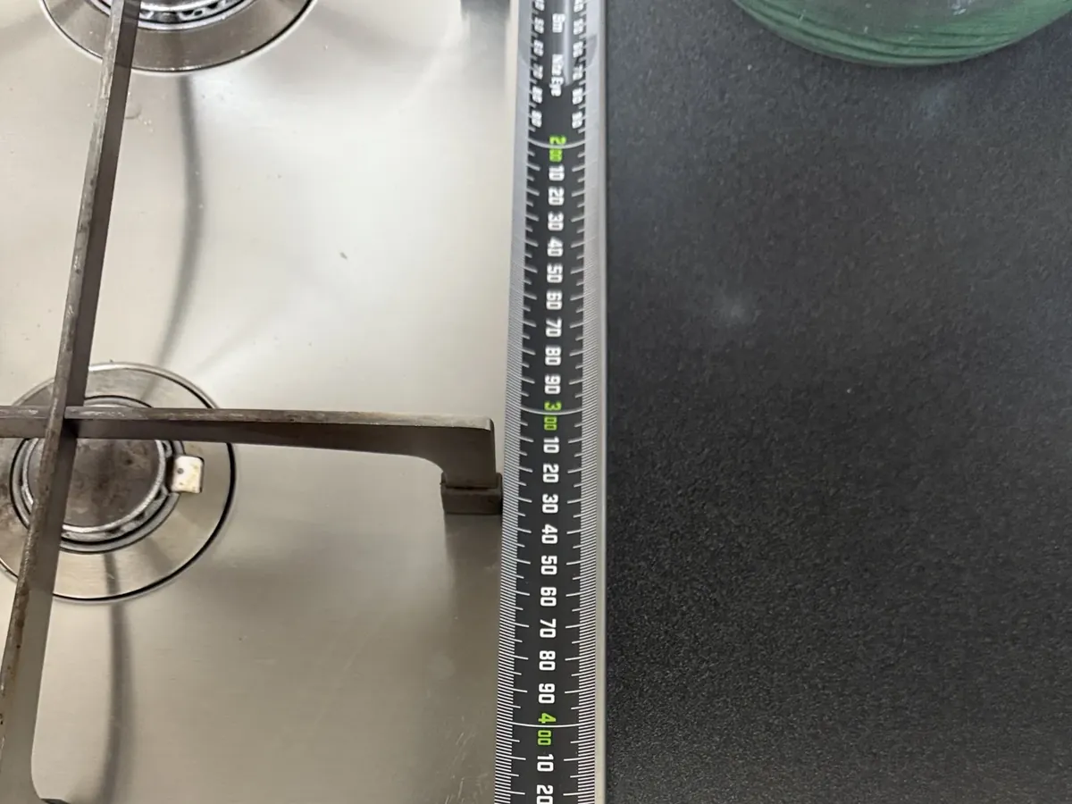 Tape measure across a stainless gas cooktop, measuring the bench cut-out in Bankstown