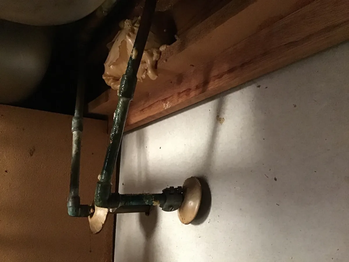 Old brass valves and corroded copper pipework under a bench in Greenfield Park
