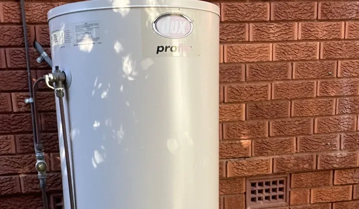 Dux Proflo electric storage tank standing against a red brick wall in Blacktown