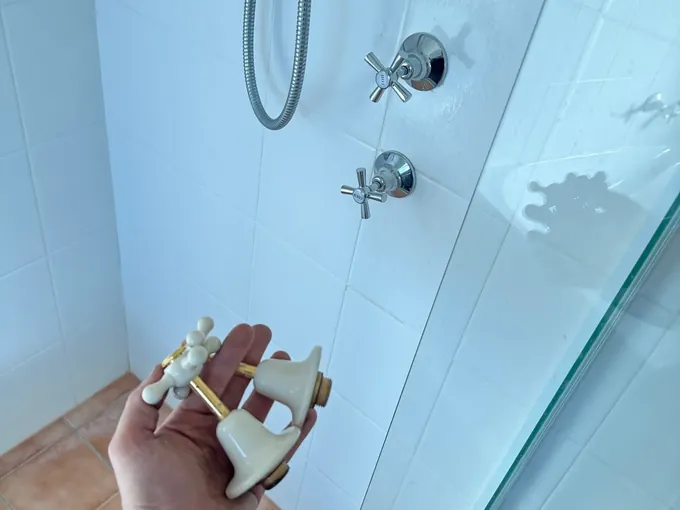 Plumber holding the old tap spindles taken out of a shower in Prestons