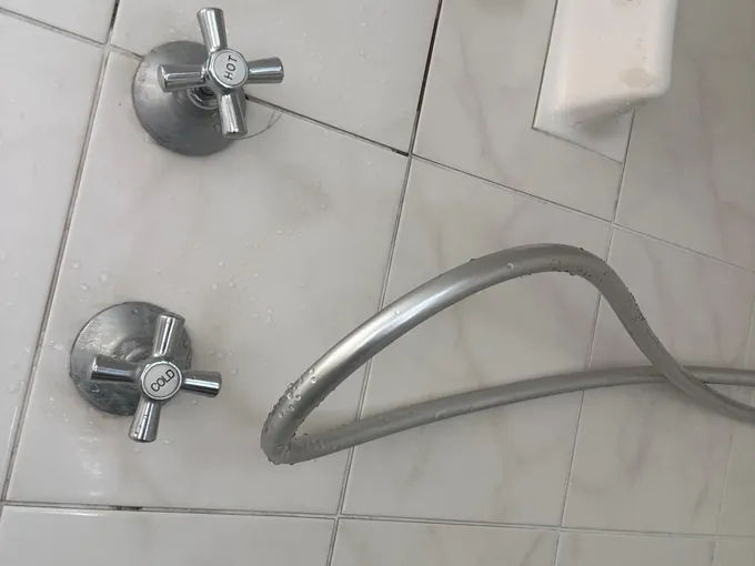 Hot and cold taps and the shower hose on a tiled wall in Castle Hill